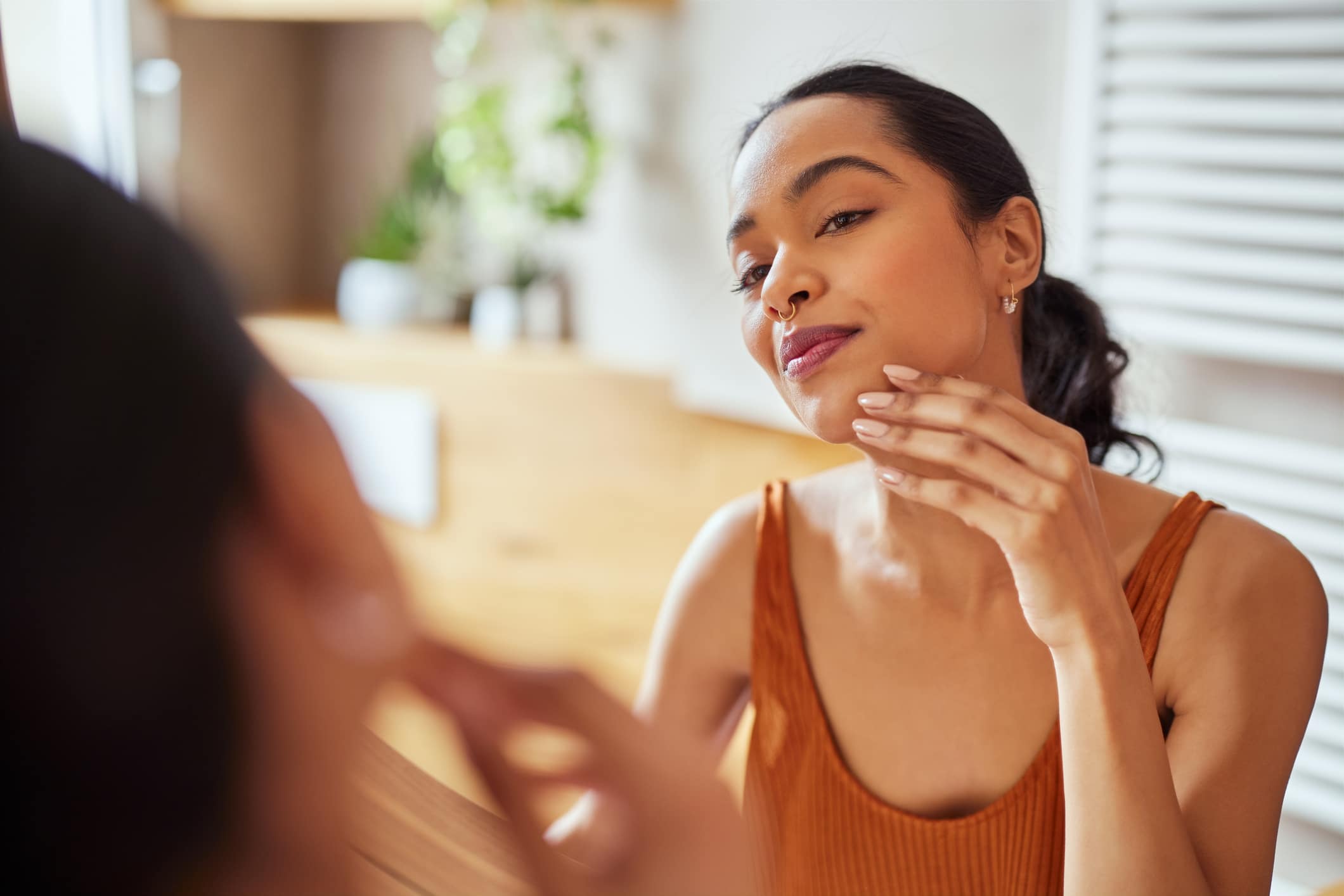 Woman examining her skin in a mirror, related to chemical peels at TRU Medical Aesthetics.