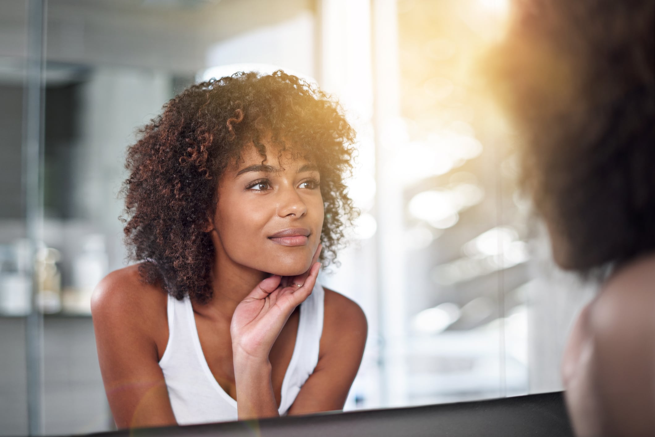 Woman looking at her reflection in a mirror with a thoughtful expression.