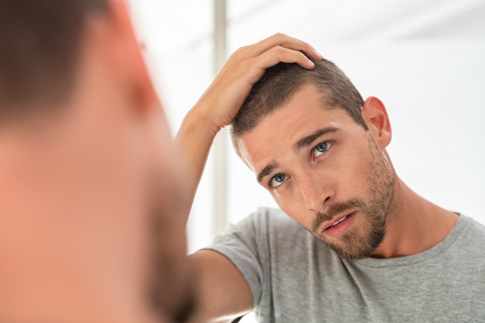 Man examining his hairline in the mirror.